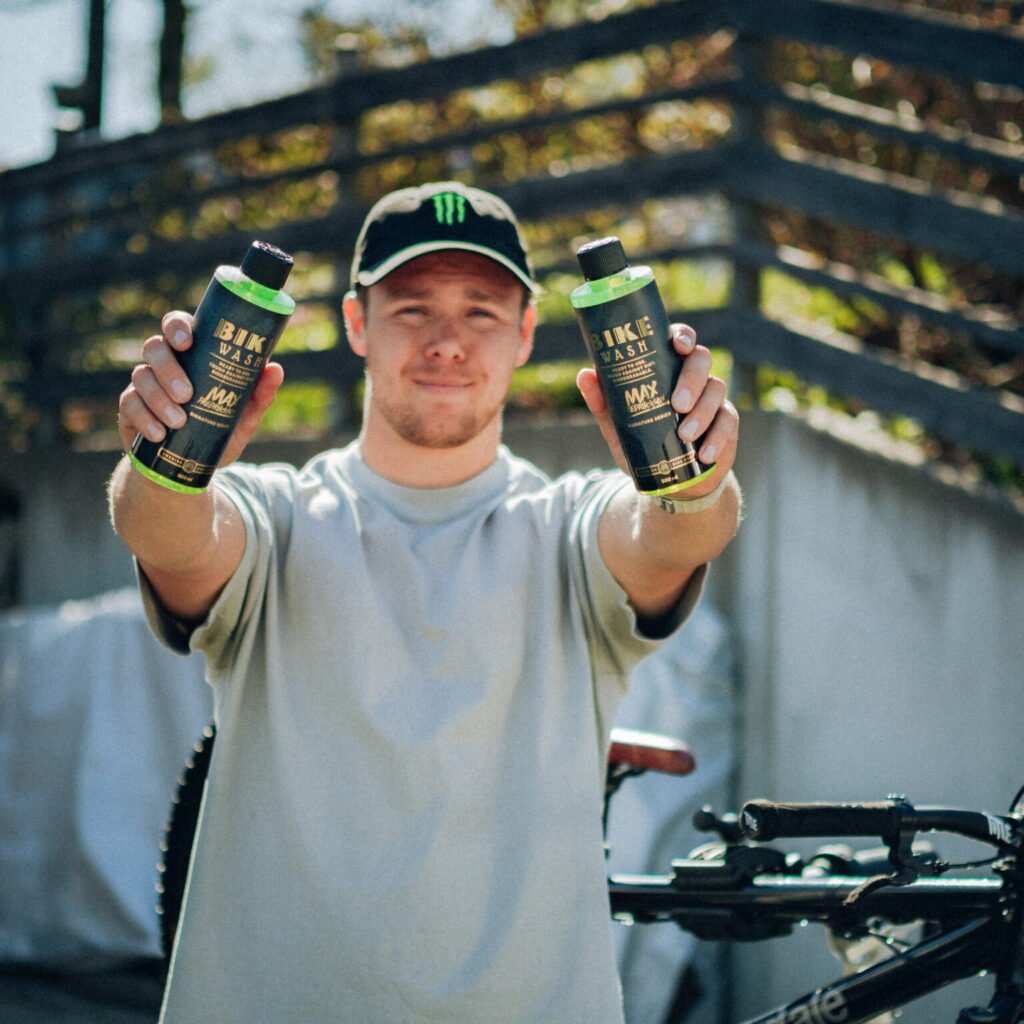 Man med cykelprodukter ler utomhus.